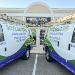 Doodlebuggers service vans parked outside a fireplace showroom, showcasing chimney and outdoor living services in Pensacola and Destin.