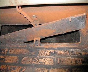 Rusty fireplace damper showing airflow control mechanism in a brick chimney.