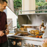 Men grilling outdoors with a stainless steel grill, showcasing outdoor cooking and socializing.