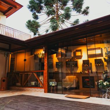 Modern house with a cozy patio and glass wall, featuring indoor seating and decor.