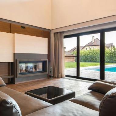 Spacious modern living room with glass doors opening to a poolside area.